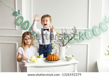Little boy with a girl in white shirts having fun at the Easter table