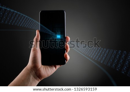 Hand holding a cell phone with embedded SIM card on gray background. Creative concept, gadget receiving data.