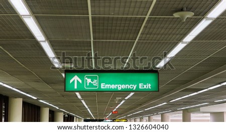 Emergency exit information board sign with white character on green background at international airport terminal.