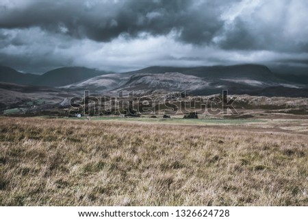 Dark, dramatic sky with rain clouds over beautiful mountain valley with sunlight painting on hills slopes.Beautiful scenery of English Lake District.Majestic view.Landscape photography UK.