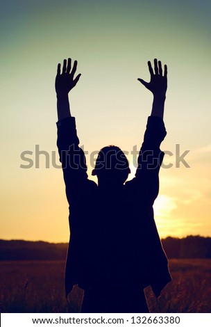 Vintage and Toned Photo of Praying Man on the Evening Sky Background