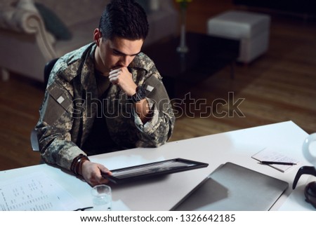 Sad American military officer looking at national flag in picture frame.