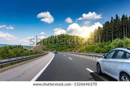 Car driving on highway surrounded by picturesque mountains.