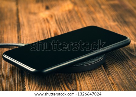 Charge your smartphone on the charging pad. Wireless charging on wooden table. rendered image