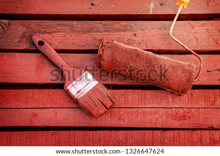 Painted wood with painting equipment paint. roller and brush handle top view on a red wooden background. in the construction of a wooden house original and ancient style.