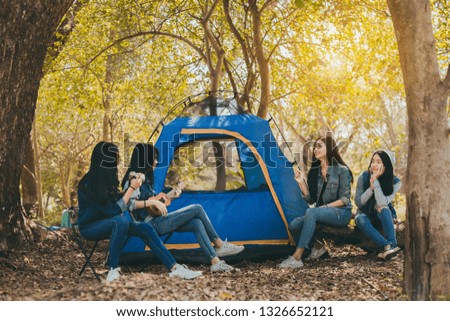 Group of Young Asian women camping and resting at forest playing ukulele,take a photo happy on weekend.