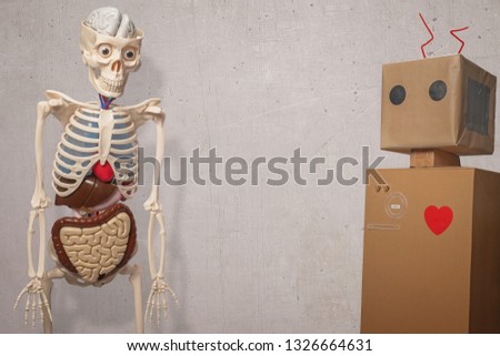 Skeleton and toy robot isolated on a stone texture wall with copy space and room for text or a person in the middle of the frame.