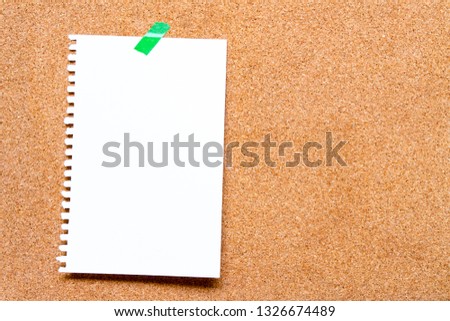Empty paper sheet with white texture and green masking tape on  brown cork board surface. Copy space for add text or art work designs.