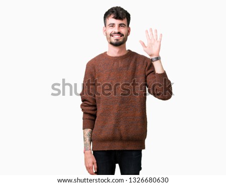 Young handsome man wearing winter sweater over isolated background showing and pointing up with fingers number five while smiling confident and happy.