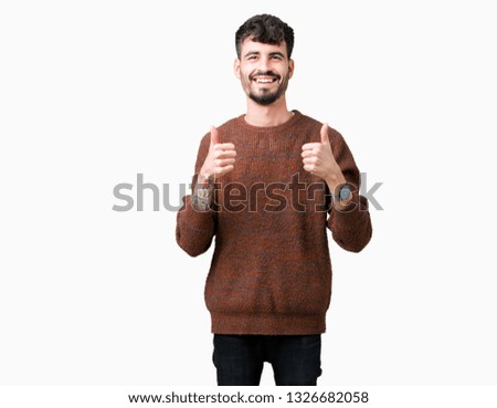 Young handsome man wearing winter sweater over isolated background success sign doing positive gesture with hand, thumbs up smiling and happy. Looking at the camera with cheerful expression, winner 