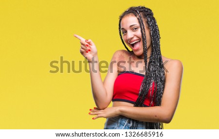 Young braided hair african american with pigmentation blemish birth mark over isolated background with a big smile on face, pointing with hand and finger to the side looking at the camera.