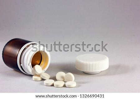 white pills near brown bottle on white background Royalty-Free Stock Photo #1326690431