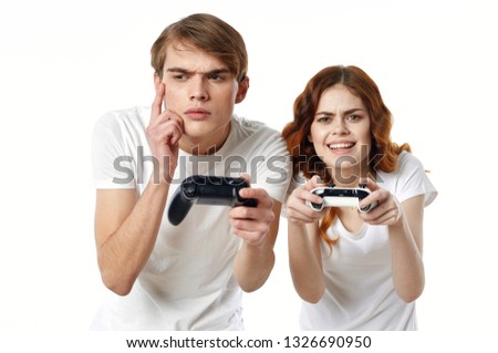 A man and a woman for a T-shirt playing with controllers in their hands in a video game console