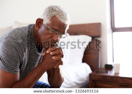Depressed Senior Man Looking Unhappy Sitting On Side Of Bed At Home With Head In Hands Royalty-Free Stock Photo #1326693116