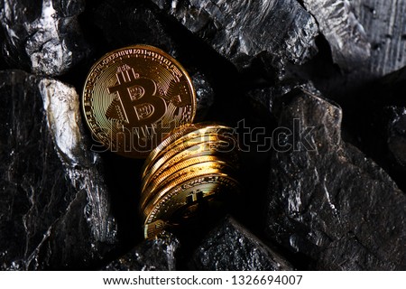 The concept of mining virtual currency. Bitcoins on a black coal background close up