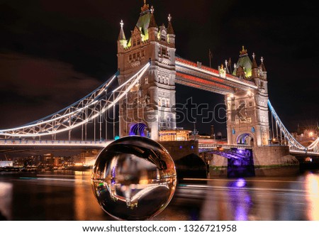 Small flipped image in Glass ball on the background of Thames river and Tower Bridge. London. Great Britain. Long exposure photography. Main focus on Lens Ball.
