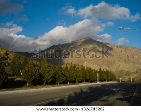 Asphalt road in the mountains, and the shadow of the clouds, under the blue sky