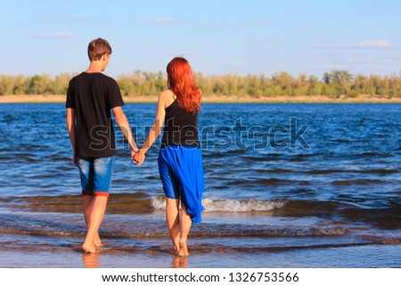 Любовная история,  пара девушка и парень держаться за руки и идут в воду.