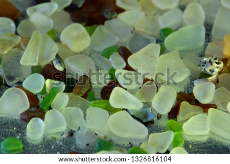 Polished glass chips on a silver reflective background with colored gels. 
