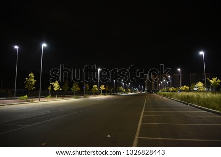 Night car parking area illuminated by lamps in the city