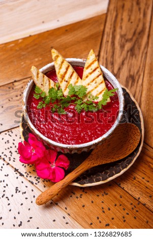 Vegan beet smoothie cream soup on plate, wooden table