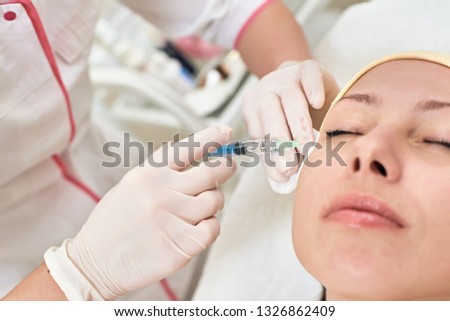 Young woman getting beauty facial injections in spa salon