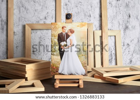 Wedding photo printed on canvas, a wooden easel and stretcher bars on table