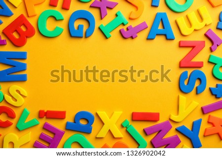 Frame made of plastic magnetic letters on color background, top view with space for text