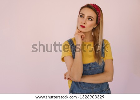 Close-up photo of pretty girl with red lips and yellow T-shirt thinking about something on pink background. Place for text. Copy space