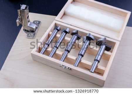 Carpentry drill, used to mount furniture hinges. A cutter used to mount furniture from chipboard. Dark background.