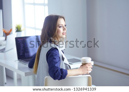 Focused attentive woman in headphones sits at desk with laptop, looks at screen, makes notes, learns foreign language in internet