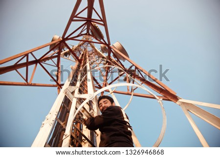 Young man standing on a metallic stairs of a mobile network tower