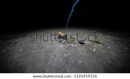 Beautiful Picture Of A Lit Cigarette Smoking Dimly Lit Room                              