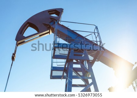 oil production tower while working in backlight against a blue sky