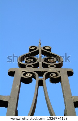 Closeup of design of wrought iron fence against a bright blue sky in Charleston, South Carolina