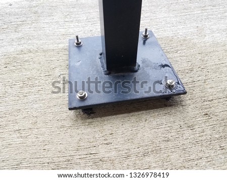 black metal post with screws on grey cement