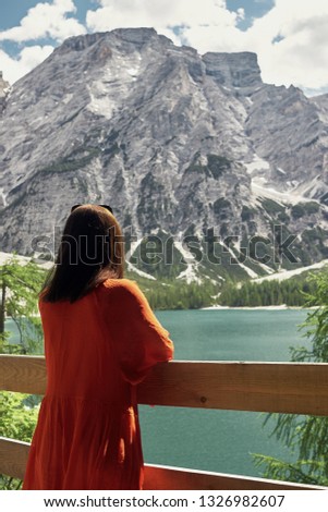Pretty girl in red dress on lake Braies, Italy