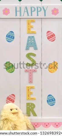 Cute and decorative happy Easter white wooden sign next to plush yellow chick