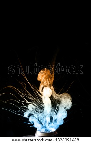Vape clouds splash on black background. Two colours fog is blue and yellow. Stock isolated color smoke with spray boiling glycerine.
