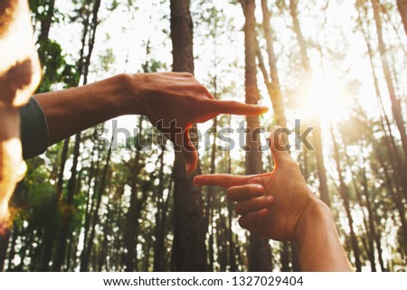 hands framing distant over view sun in forest