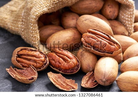 Pecan in bag on black table. Heap or stack of pecan . Pecan background. Royalty-Free Stock Photo #1327086461
