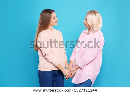 Portrait of mature woman and her daughter on color background