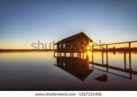 A boatshouse at a lake at sunset Royalty-Free Stock Photo #1327121426