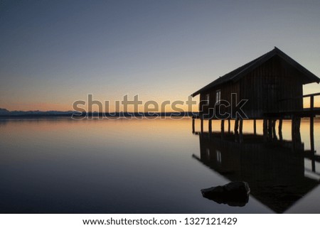 A boatshouse at a lake at sunset Royalty-Free Stock Photo #1327121429