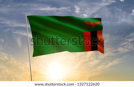 zambia flag waving in the wind against a blue sky and clouds
