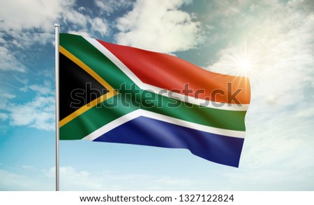 South Africa flag waving in the wind against a blue sky and clouds