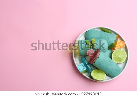 Plate with delicious spirulina popsicles and lime on color background, top view. Space for text
