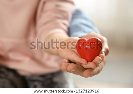 Man and his daughter holding red heart on blurred background, closeup. Children's doctor