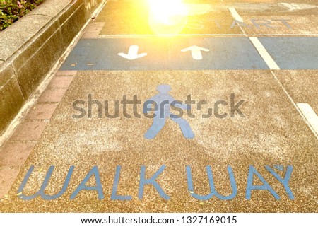 Sign walk way and arrow (up, down) on ground floor in public park with sunlight. Safety your life. Be careful to walk correct lane.