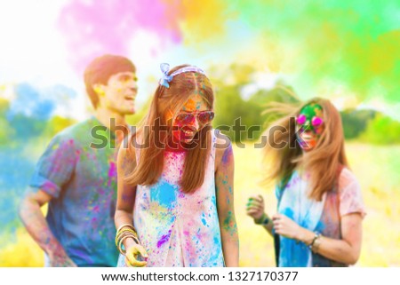 Happy holi party: sunny beautiful women females teenagers and males men in sunglasses celebrating happy holi festival in spring, summer day outdoor in green park with light leaks and colorful powder